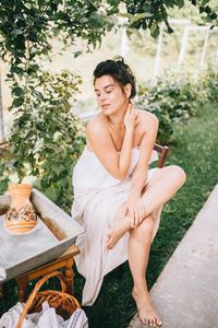 Young woman sitting on seat in yard