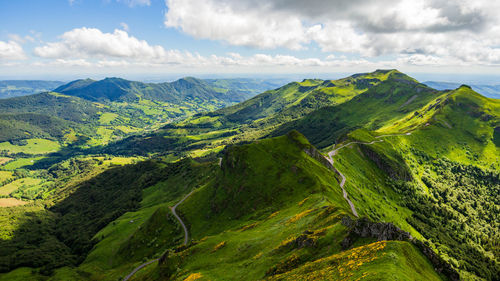 Scenic view of green mountains against cloudy sky