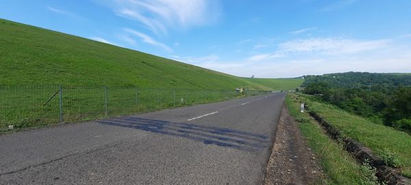 Road amidst green landscape against sky