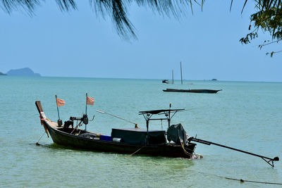 Fishing boats in sea against clear blue sky
