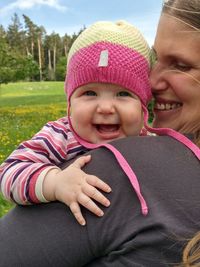 Smiling woman with baby girl on field