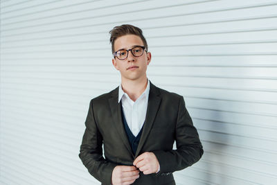 Portrait of young man standing against wall