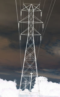Low angle view of electricity pylon against sky during winter