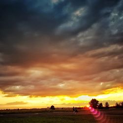 People on landscape against sunset sky