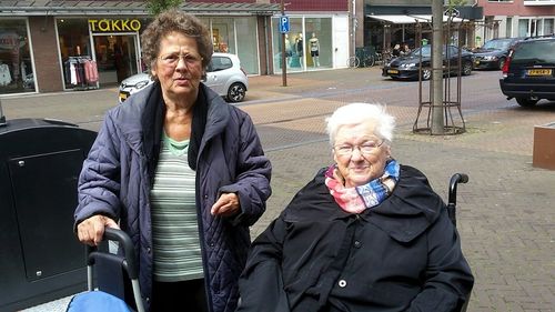 Happy friends sitting on sidewalk in city