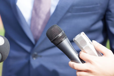 Midsection of businessman standing by microphones