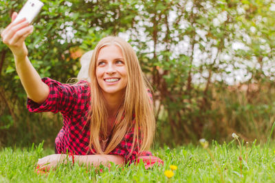 Smiling young woman taking selfie with mobile phone in park