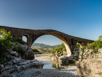 Arch bridge over river against clear sky