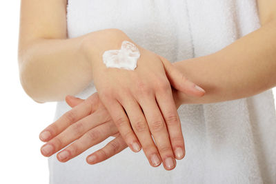 Close-up of woman holding hands over white background