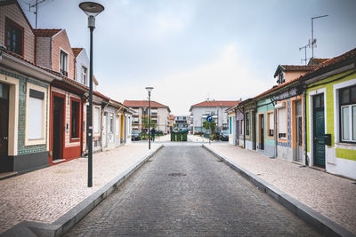 Empty road amidst buildings in city against sky