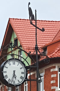 Low angle view of clock on building against clear sky