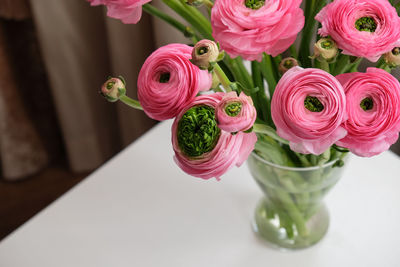 Pink ranunculus bouquet in transparent glass vase on white table. close-up. for flower delivery