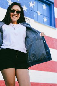 Portrait of young woman wearing sunglasses standing outdoors