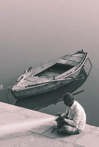 High angle view of man sitting against boat in river