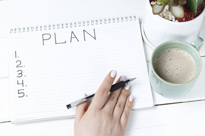 Cropped image of hand holding coffee cup on table