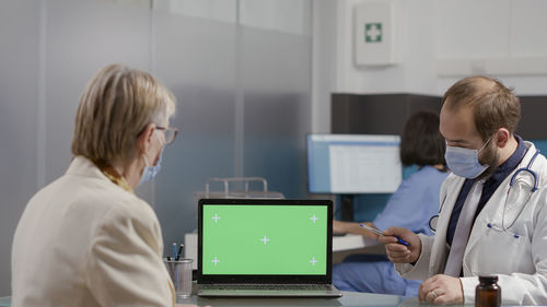 Side view of young woman using laptop while sitting in office