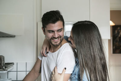 Smiling couple looking at each other while standing in kitchen
