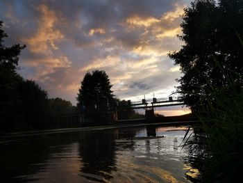 Bridge over river against sky at sunset