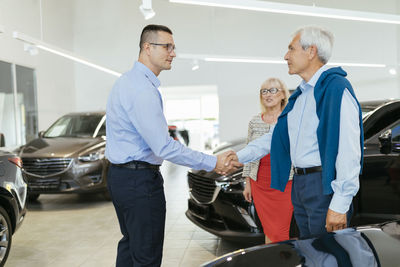 Senior couple couple talking with salesperson in car dealership