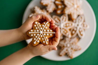 Ginger christmas cookies in children's hands on the background of the christmas tree.