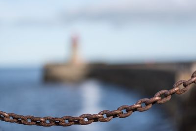 Close-up of chain against sea against sky