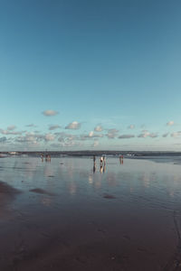 People on beach against blue sky