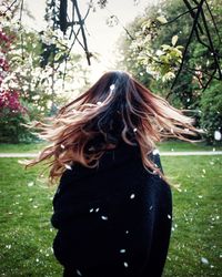 Rear view of woman tossing hair on in park