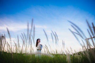 Young woman on field against sky