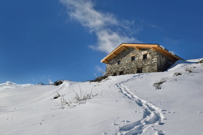 House on snow covered land against sky