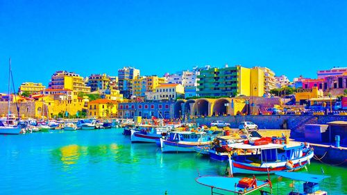 Boats moored at harbor against clear blue sky