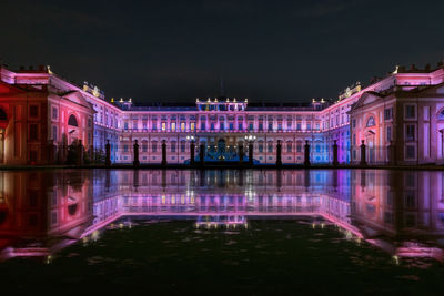 Illuminated building by lake at night