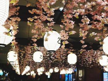 Low angle view of illuminated light bulb hanging in city