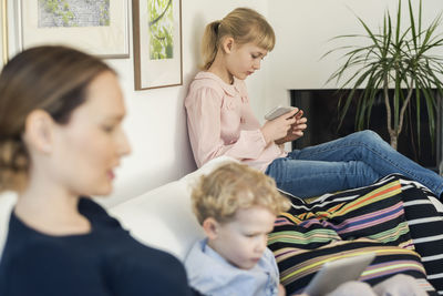 Mother and kids using technologies on sofa at home