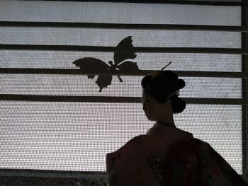 Silhouette person against window at home