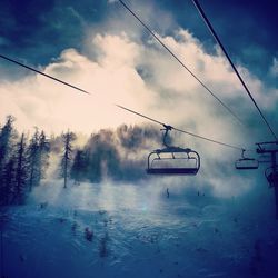 Ski lift against cloudy sky