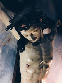 Closeup on a christ wooden sculpture, crucifix and pastel tones and colors with copy space 