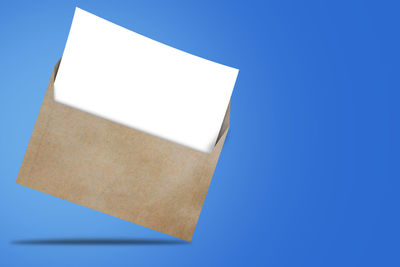 Low angle view of empty paper against blue background