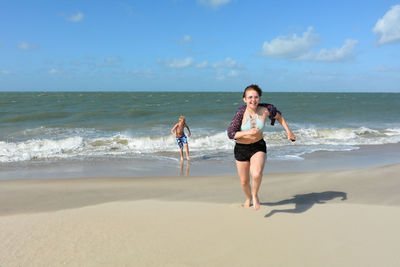 Full length of friends on shore at beach against sky