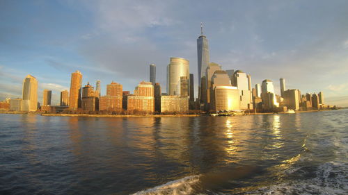 Sea by modern buildings against sky in city