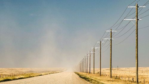 Road amidst field against clear sky