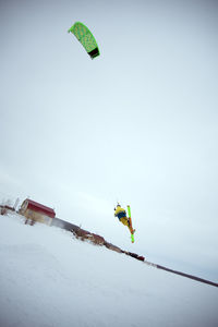 Low angle view of person paragliding on snow against sky