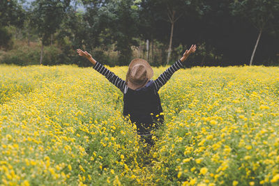 Full length of person standing on yellow flower in field