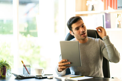 Young man using mobile phone while sitting on table