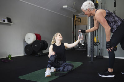 Happy women holding water bottle at health club