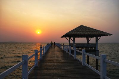 Pier over sea against sky during sunset