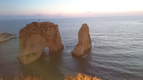 Rock formation in sea against sky