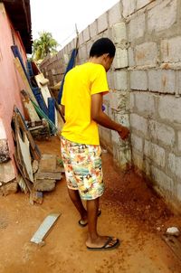 Side view of boy standing against wall