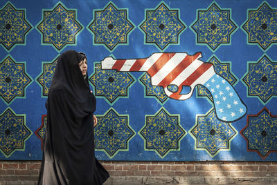 Woman standing against graffiti wall