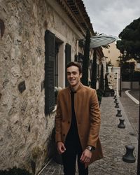 Portrait of young man standing against building