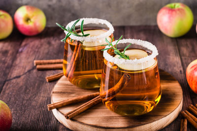 Homemade organic apple cider with cinnamon and rosemary in glasses on the table